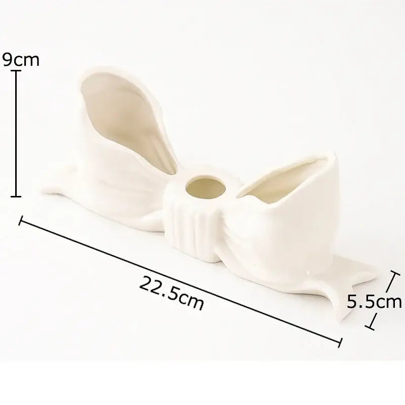 A white ceramic bowknot candle holder with a central circular opening and flared sides for dining room decorbites decor