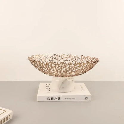 A rose gold coral disc pedestal metal bowl with intricate lace design on a white marble base for dining room decorbites coral disc