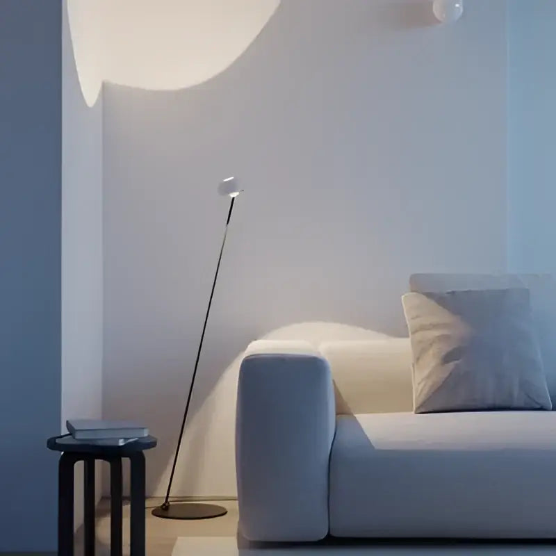 A rose gold decorbites designer fishing floor lamp with a sleek metallic stem and spherical white light for living room decor