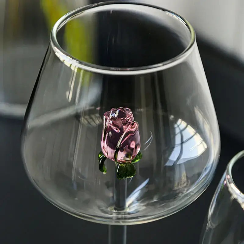 A delicate pink glass decorbites 3d rose with green leaves inside a clear rose stemware wine glass for dining room decor