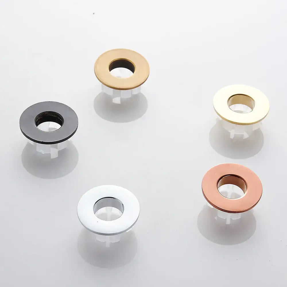 Round brass sink overflow cover set with five metallic button fasteners in black white gold rose gold and silver tones