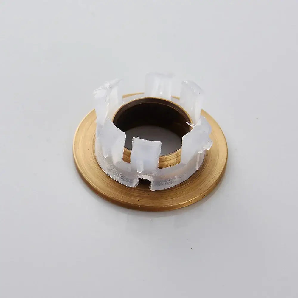 Gold-toned metal brass sink overflow cover with translucent white plastic retaining ring for decorbites brass sink insert