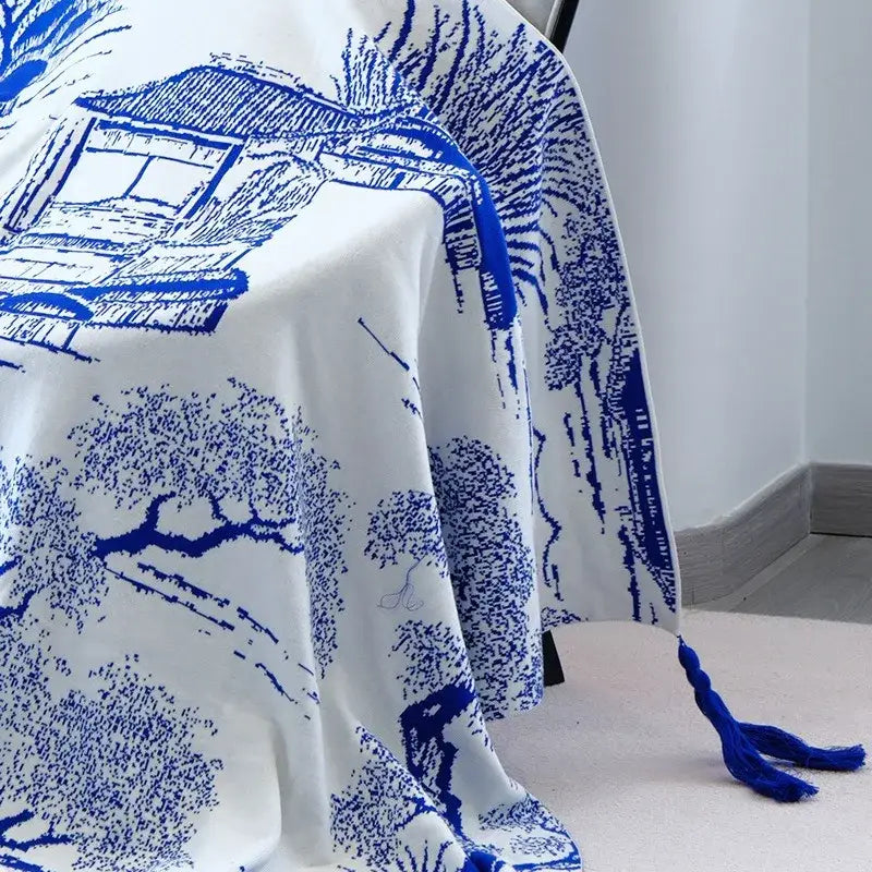 White fabric knitted sofa blanket with blue ink-style chinese landscape illustrations and matching tassel end