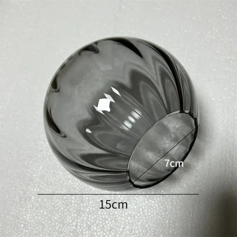 A translucent gray decorbites glass ball pendant lamp with swirling ribbed design and open base for living room decor