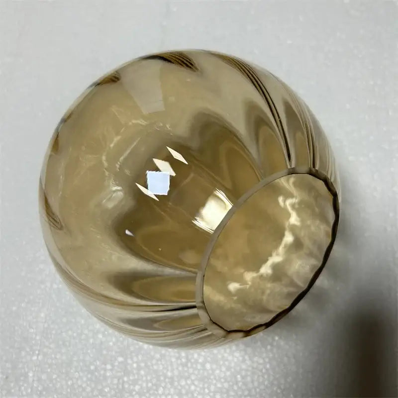 A translucent amber decorbites glass ball pendant lamp with smooth rounded shape and vertical ridges for living room decor