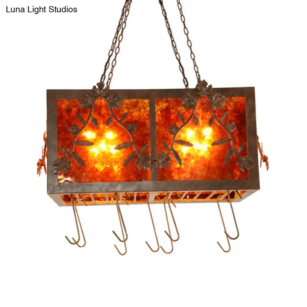 Rectangular island light with amber leaf-patterned glass panels and dark metal frame for rustic dining room lighting