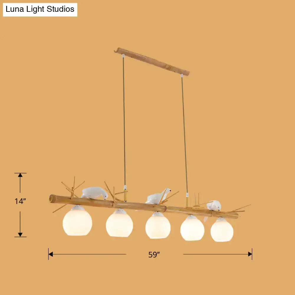 DecorBites modern cream glass wood pendant light fixture with five frosted globes and white bird deco on dome island