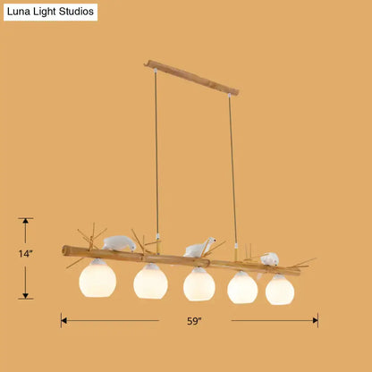 DecorBites modern cream glass wood pendant light fixture with five frosted globes and white bird deco on dome island