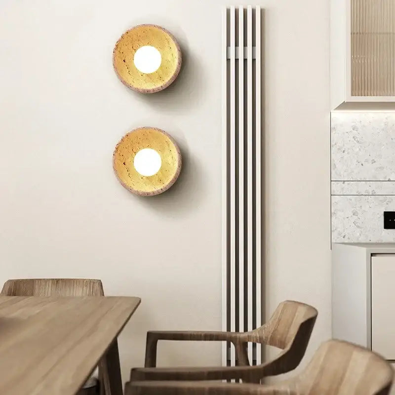 Two circular wall lights with warm cork finish and glowing centers on rustic beige travertine base decorbites led wall light