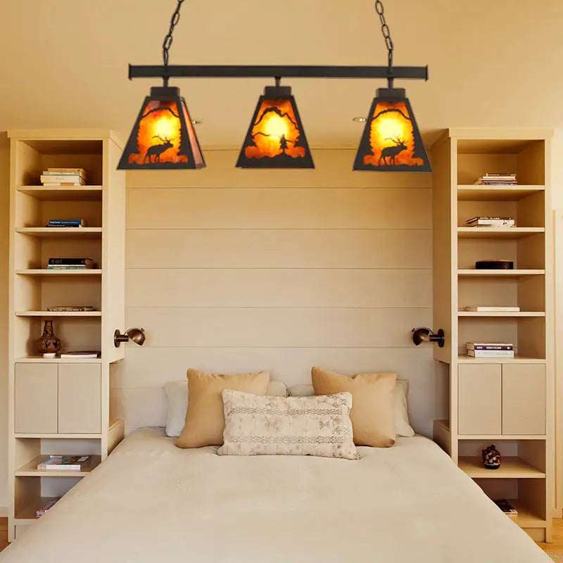 Rustic black metal pendant light with three amber backlit triangular glass shades and deer silhouette scene for dining room