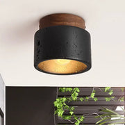 Rustic black travertine ceiling light with concrete texture and wooden top featuring warm gold interior for entrance hallway decor