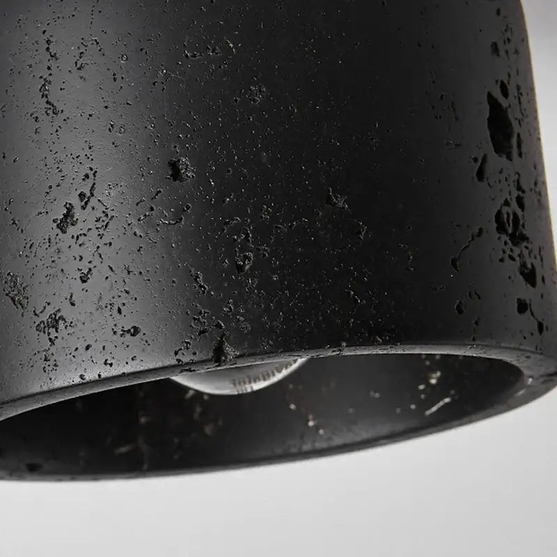 Rustic black travertine ceiling light with black matte cylindrical pendant and textured speckled surface for hallway decorbites black travertine