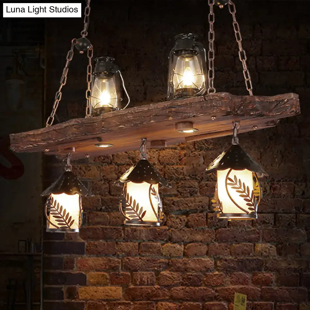 Rustic black wood lantern island ceiling light with three hanging leaf-patterned metal lanterns and amber glass lamps