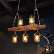 Rustic black wood lantern island ceiling light with three amber glass hanging lanterns and two suspended oil lamps