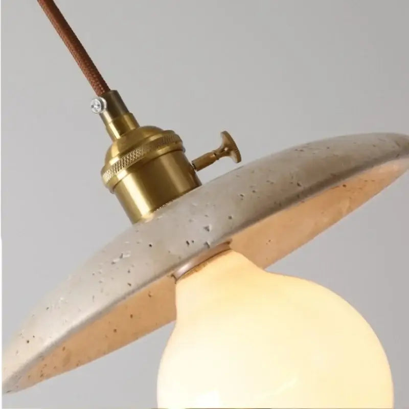 Rustic brass and ceramic glass ball led pendant light with warm-toned speckled concrete and brown fabric cord