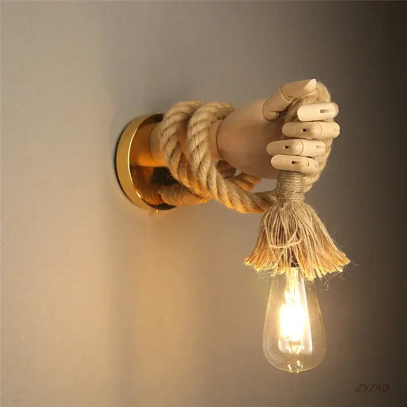 Rustic brass hand shape wall lamp with wooden hand gripping beige hemp rope and exposed edison bulb wall light