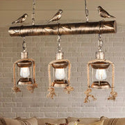 Bronze finished metal caged island pendant light with three lanterns and carved birds for kitchen or dining island lighting