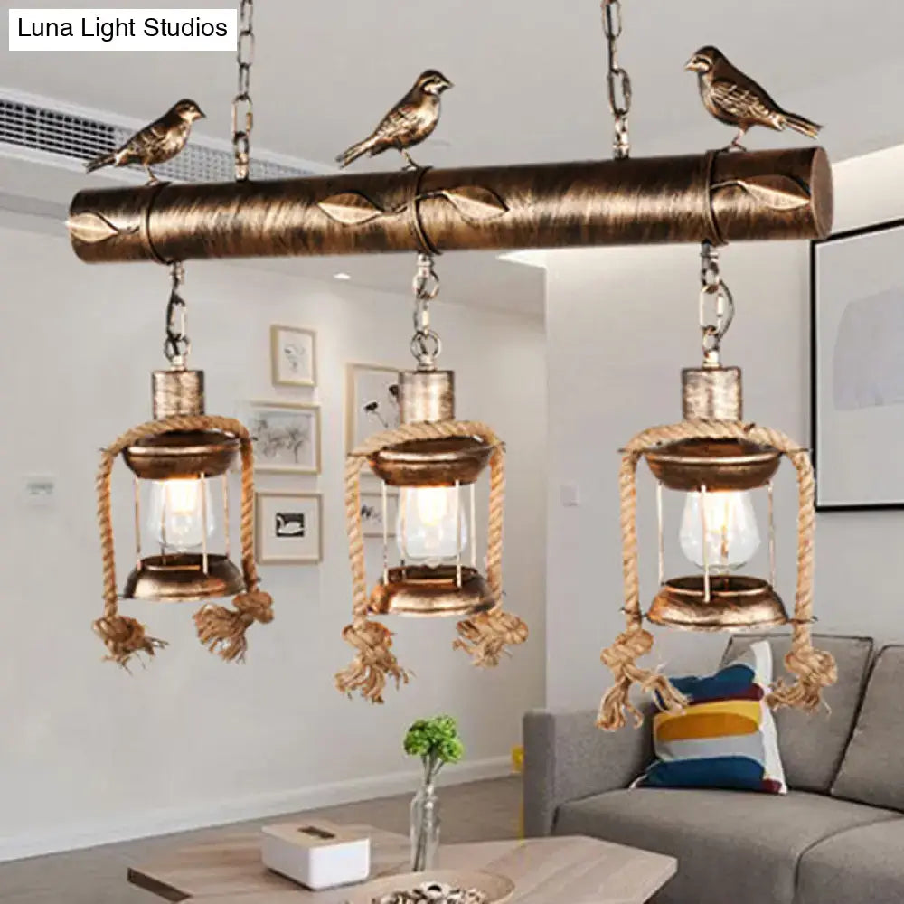 Antique brass coastal style metal caged island pendant light with three lanterns rope detailing and bird figurines