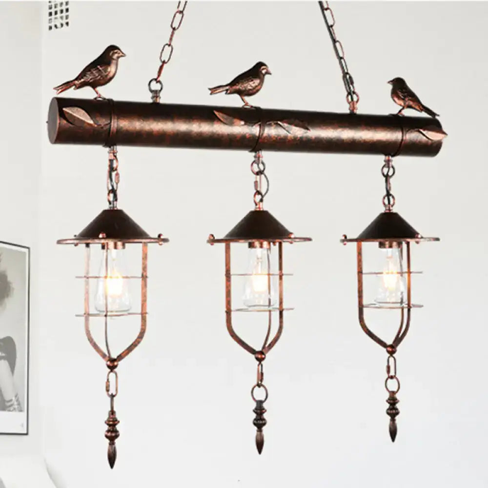 Copper-toned DecorBites metal caged island pendant light with three hanging lanterns and sculpted birds in bronze weathered copper