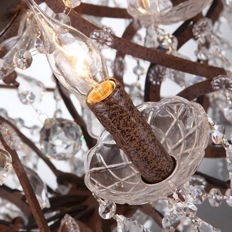 A clear glass candle-style bulb with warm glow in a rustic bronze decorbites crystal earth birdcage chandelier