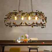 Rustic bronze iron bird cage chandelier featuring exposed filament bulbs and hanging greenery for dining room decorbites iron bird cage