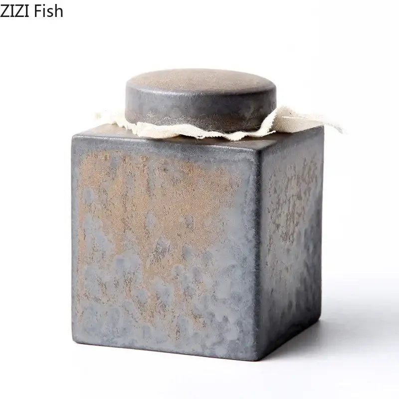 Rustic earth toned ceramic tea canister with matte gray and brown glaze and fabric band for kitchen storage