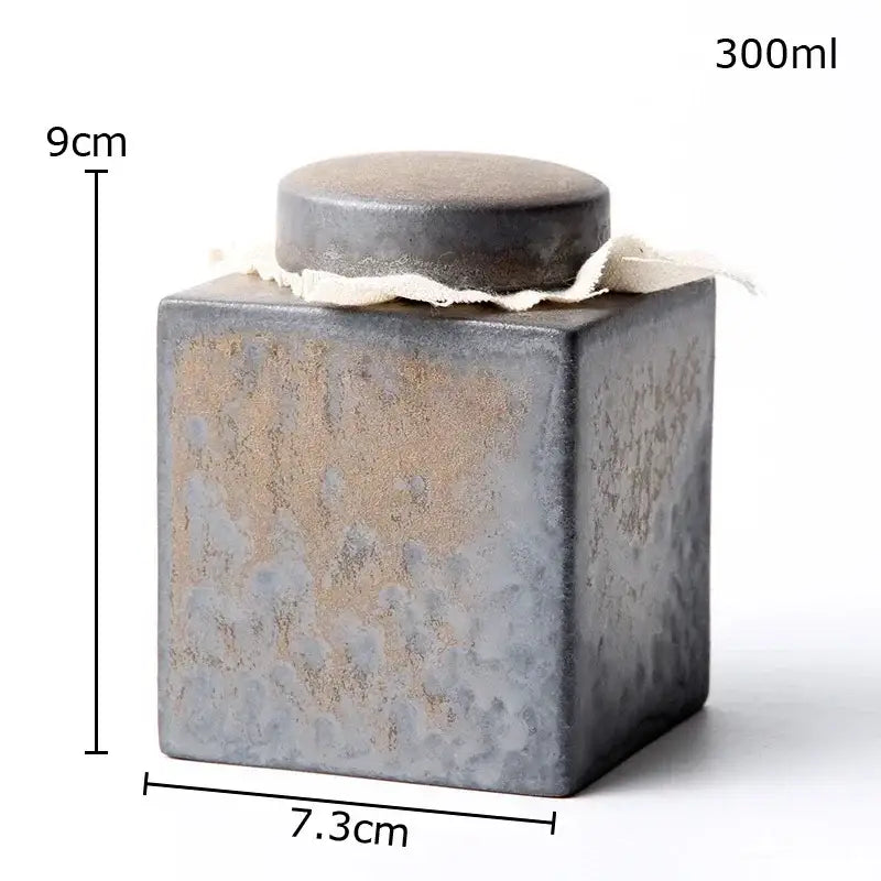 Rustic earth toned ceramic tea canister with matte gray and brown glaze and fabric tied lid for kitchen storage