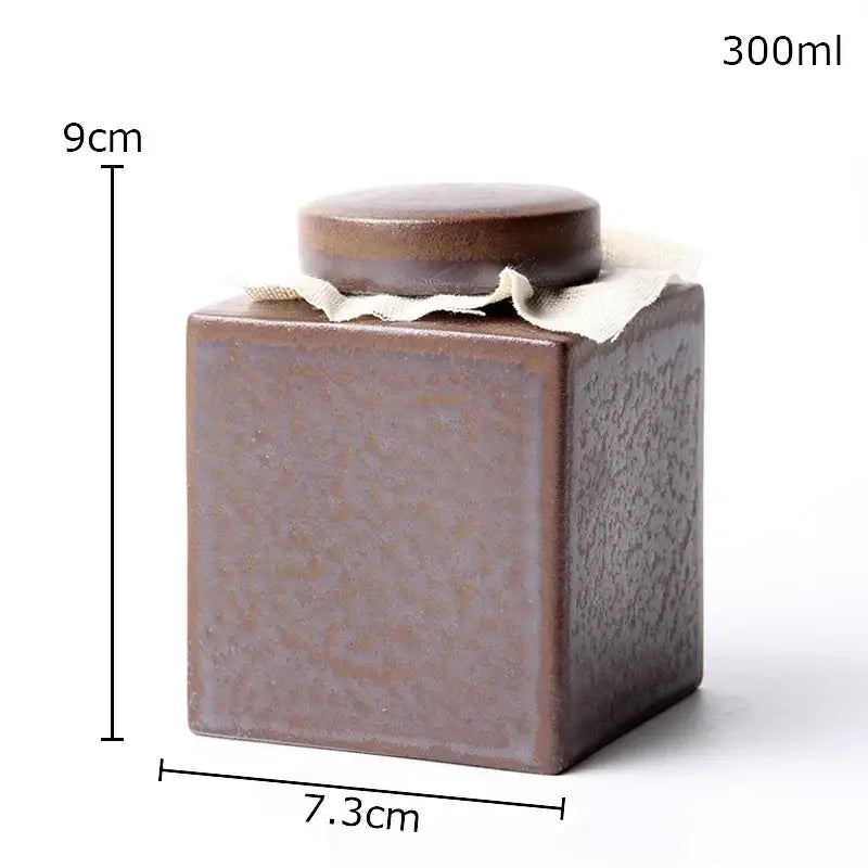 Rustic earth toned brown ceramic tea canister with matching lid and light fabric tie for kitchen storage jar