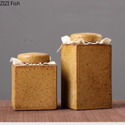 Two rustic earth toned ceramic tea canisters with textured surfaces and fabric tied lids for kitchen storage