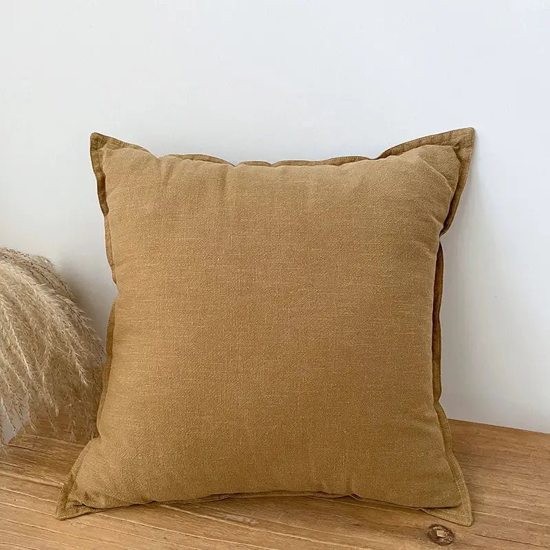 A square mustard-yellow linen fringed pillow cover with textured surface and stitched edges for rustic living room decor