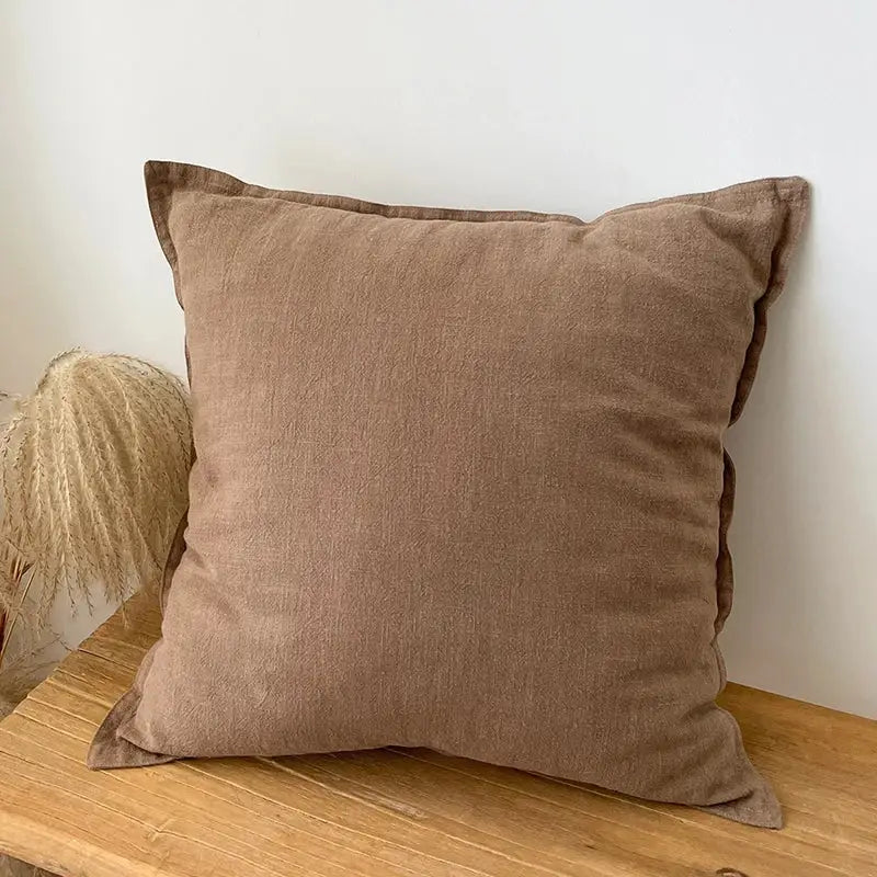 A soft square brown linen fringed pillow cover with a textured surface for rustic earthy tones living room decor