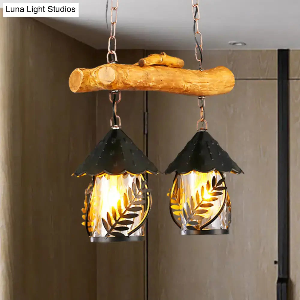Rustic wooden branch pendant light with two black metal leaf-patterned lanterns and white fabric clear glass shade for farmhouse lighting