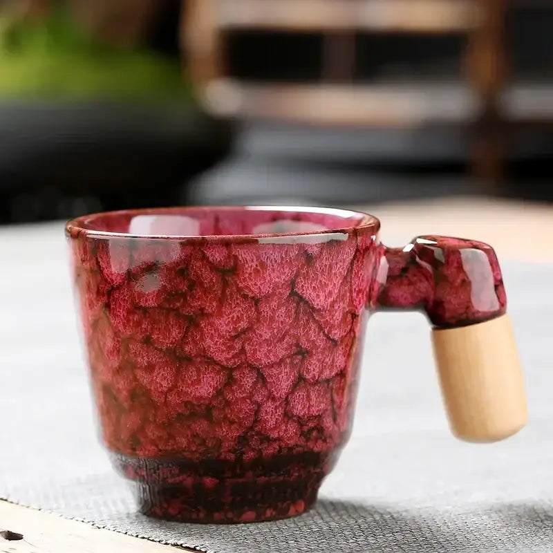 Rustic ceramic latte mug with vibrant red crackled glaze and light wood handle for kitchen drinkware use