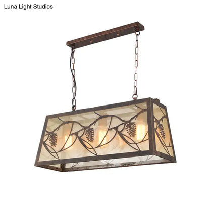 Rectangular island light fixture with bronze metal frame and amber stained glass panels featuring pinecone motifs