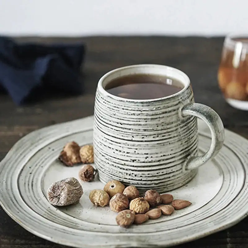 Rustic grayish white ceramic dish bowl set featuring a white speckled ridged mug filled with dark liquid