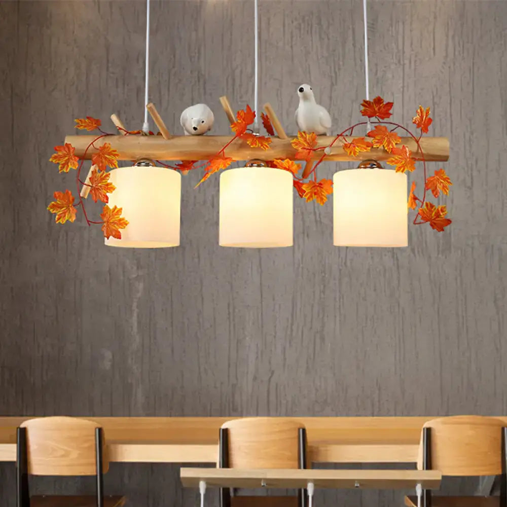 A rustic decorbites™ ivory glass wood island pendant with maple green leaf and bird décor featuring three white shades