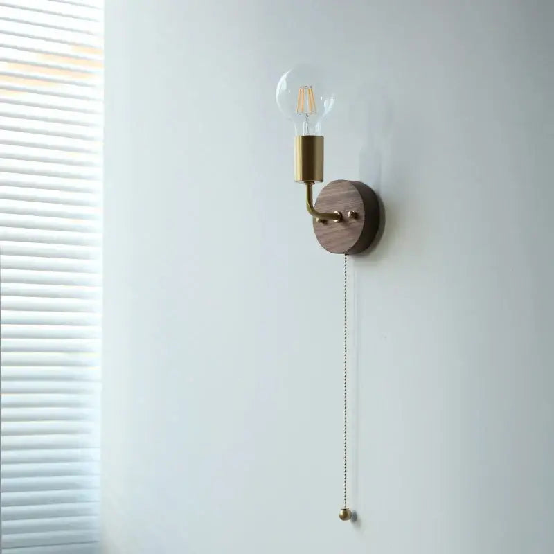 Rustic led walnut wood wall sconce with warm brass arm and round walnut wood plate featuring exposed filament bulb