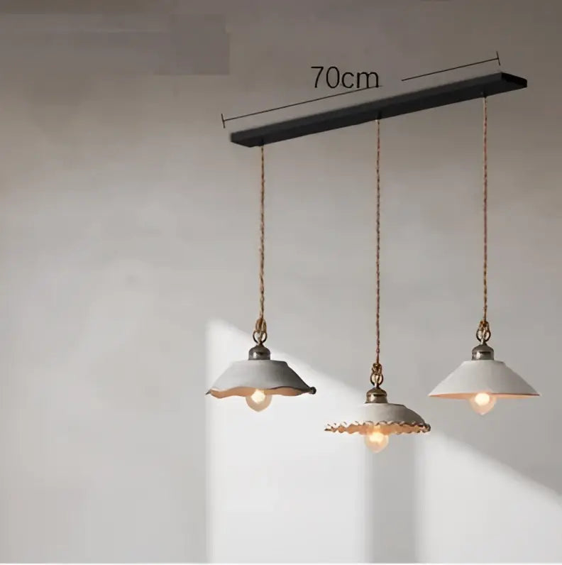 Industrial-style pendant light with matte black bar, brass chains, and off-white ceramic shades in cement loft style decorbites