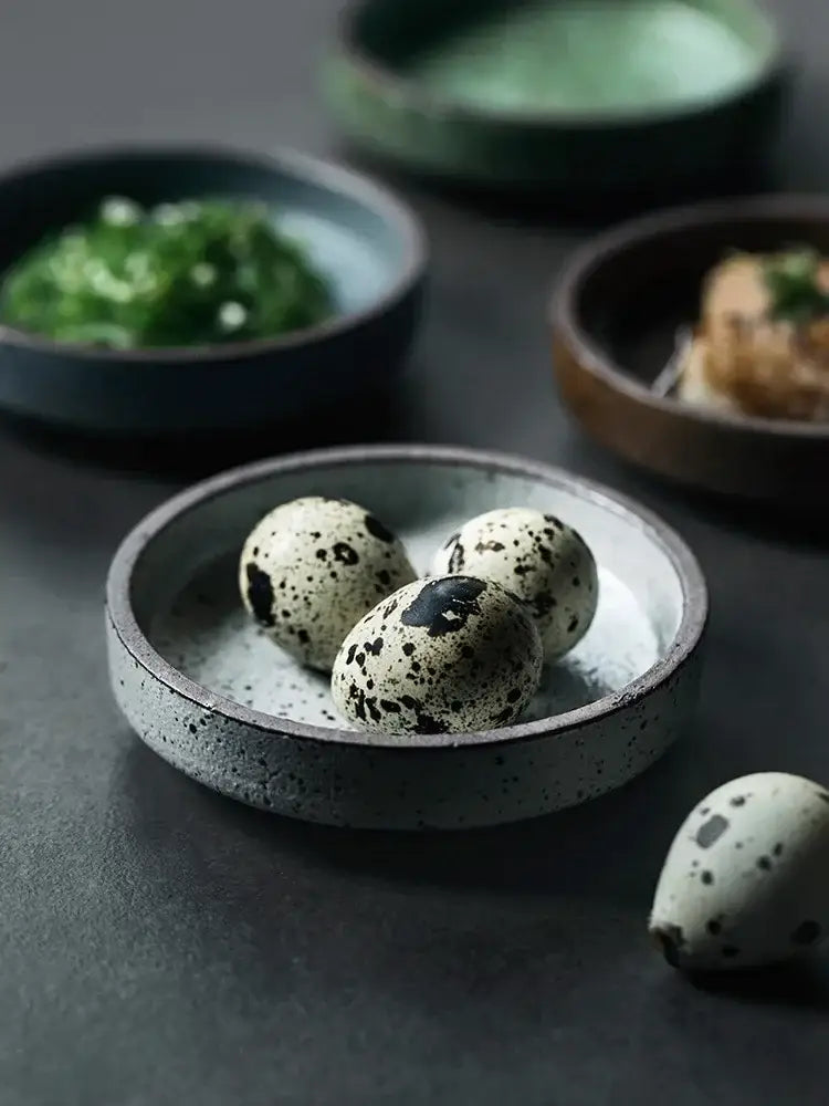 Rustic speckled gray ceramic sauce dish holding three black-spotted quail eggs decorbites ceramic sauce dishes