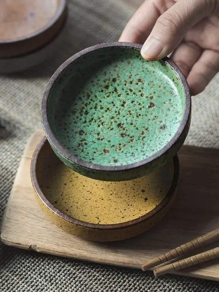 Hand holding a ceramic sauce dish with speckled green glaze and dark brown rim from decorbites ceramic sauce collection