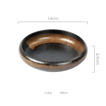A sleek oval ceramic kimchi plate with glossy black glaze and earthy brown speckles along the rim