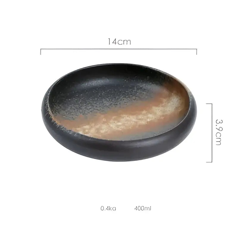 A sleek oval ceramic kimchi plate with a glossy black exterior and gradient brown to gold interior for dining use