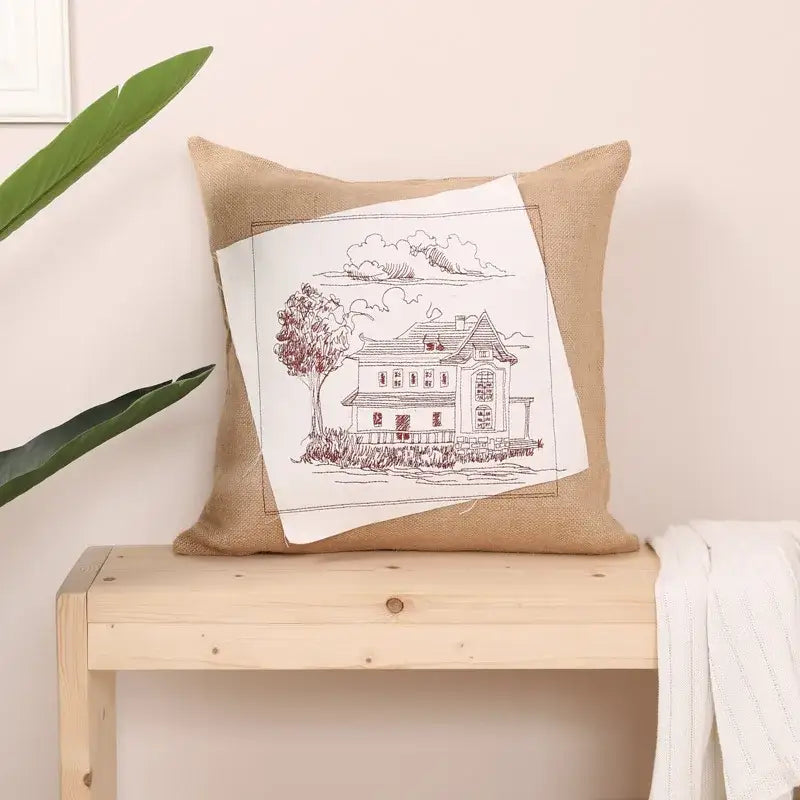 Rustic tan burlap pillow cover with white embroidered patch featuring a black and red house sketch fashion pillow cover