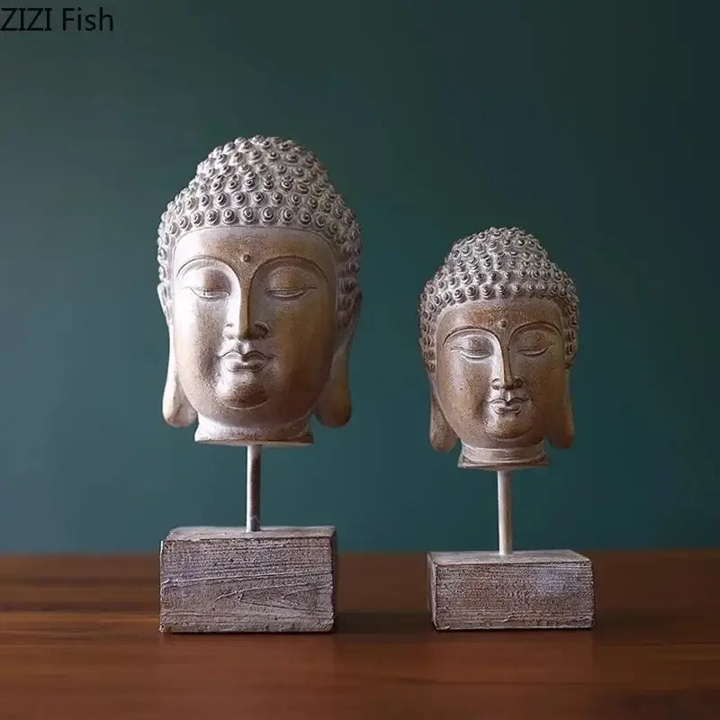 Two weathered bronze buddha head statues on rustic wooden bases with slender metal stands for living room decor