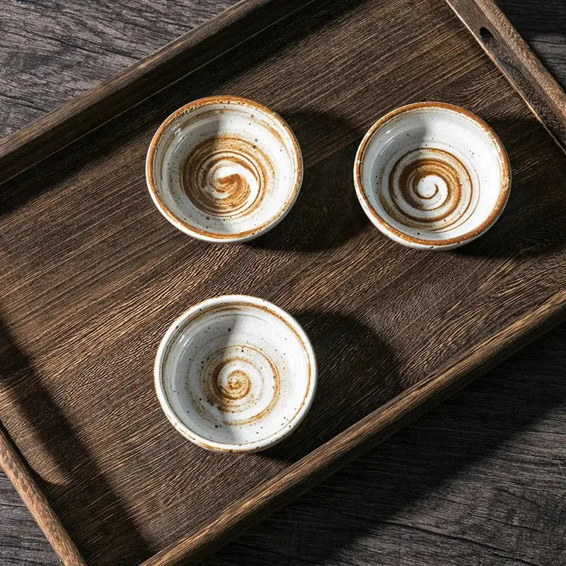 Three rustic white speckled ceramic seasoning sauce dishes with brown spiral patterns on a dark wooden tray decorbites ceramic seasoning