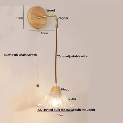 Rustic wood and brass wall light with clear glass bell shade and pull chain switch mounted on circular wooden backplate