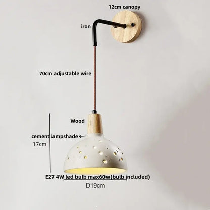 Rustic wood and gray wall light fixture with a white ceramic perforated pendant lamp and iron arm in bedroom sconce design
