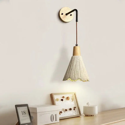 Rustic wood and gray wall light fixture with wooden base and beige woven conical shade with scalloped edge and pull chain