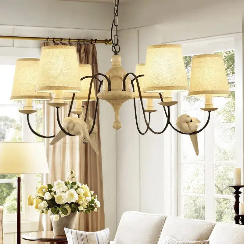 Beige wrought iron decorbites bird lamp chandelier with six cream fabric shades and white bird figurines for dining room