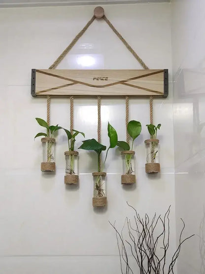 Light wood wall-mounted wooden stand with rope suspension and five glass planter vase vials holding green plants